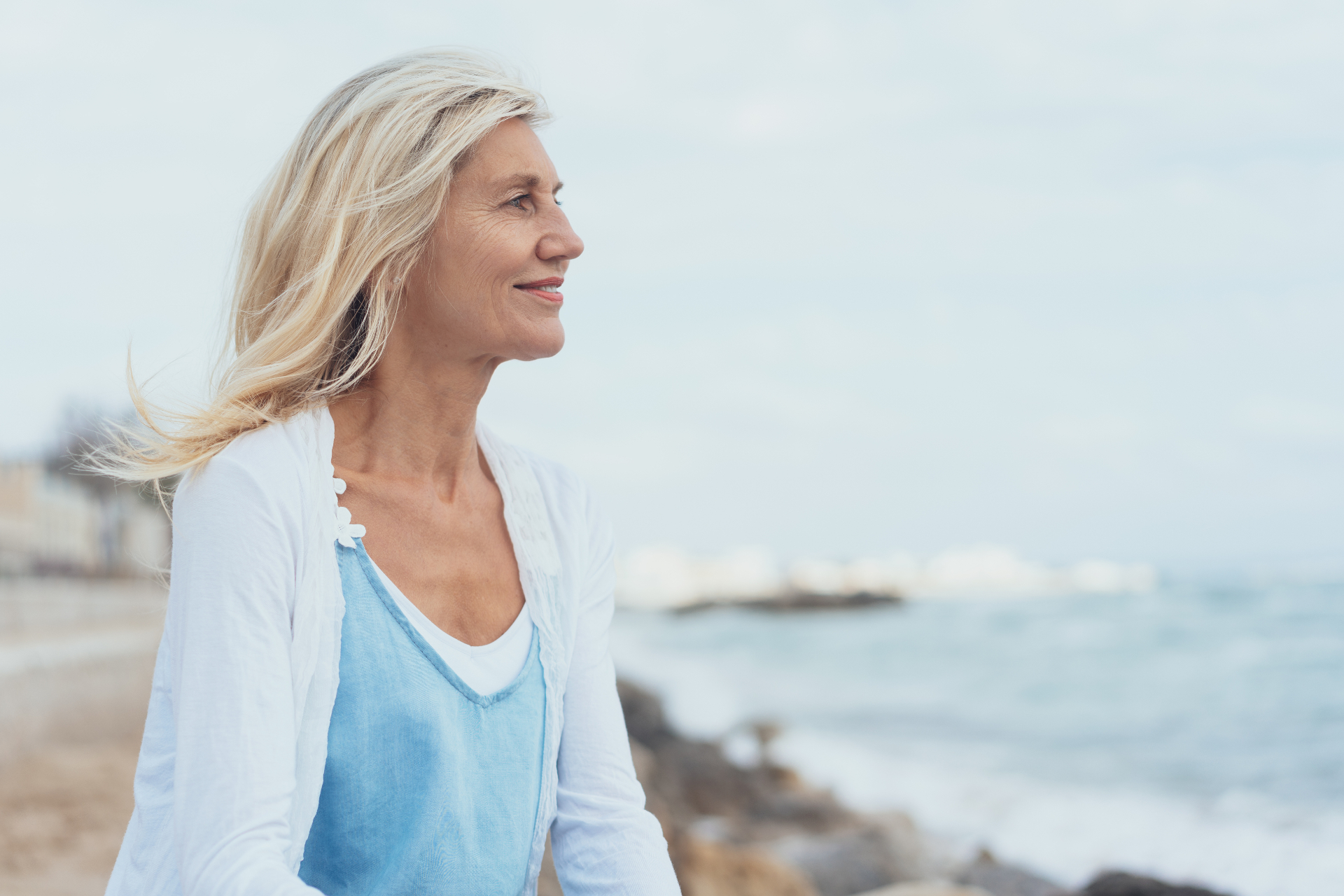 Woman in midlife standing by the ocean, looking calm and strong